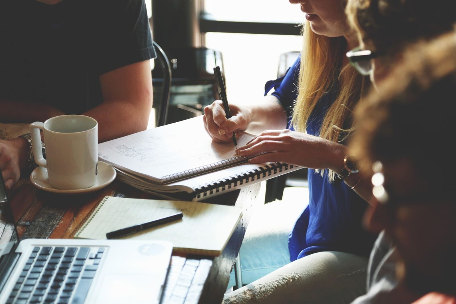 Founders planning in a notebook at a shared table in warm light